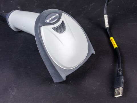 A Honeywell handheld barcode scanner with a pistol-grip handle and a trigger inside a guard loop. Source Wikimedia Commons (Raimond Spekking, CC BY-SA 4.0).