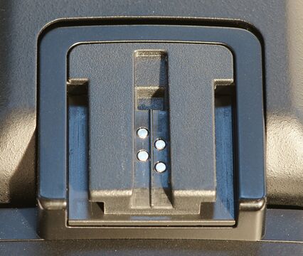 A camera flash and accessory shoe: the rectangular dovetail-rail mount with center contacts. Source Wikimedia Commons (Alex.K.NY, CC BY-SA 3.0).
