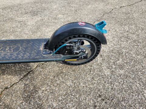 The rear of the scooter after the tire change: deck, fender, solid honeycomb rear tire, disc brake, and teal rear hook. None of this is high voltage or safety-sealed, and the rear tire is a routine wear item. Reaching it is the job that ran into the security fasteners shown below.